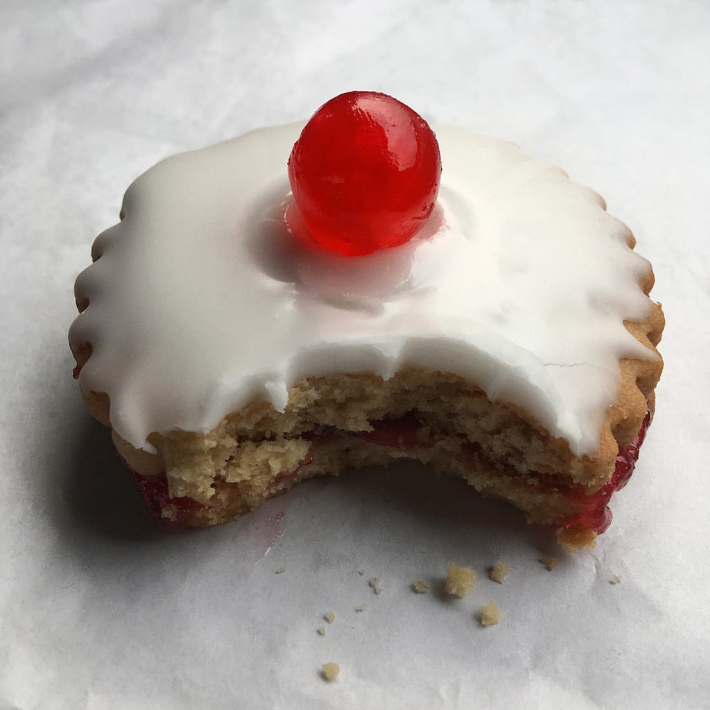 close up half eaten empire biscuit with icing and cherry moffatt scotland